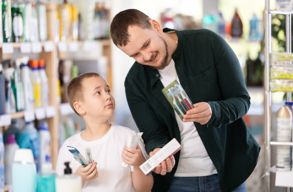 Schoolboy son and dad are choosing toothbrush in store