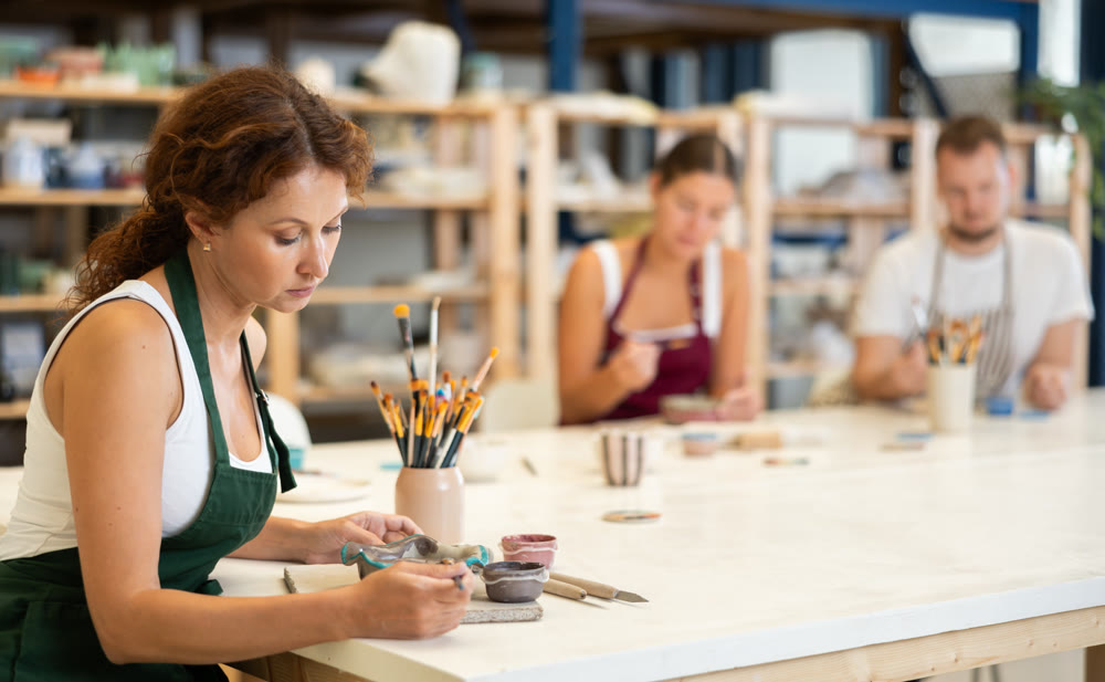 Three craftsperson are busy painting clay products