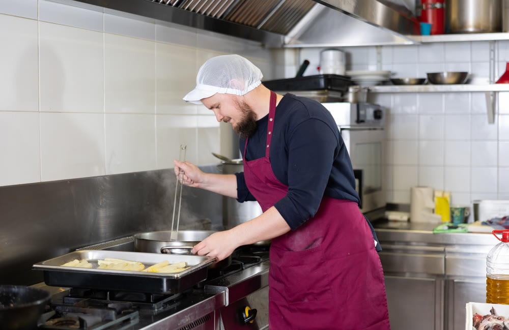 Bearded chef cooking meals for sale in deli department of supermarket