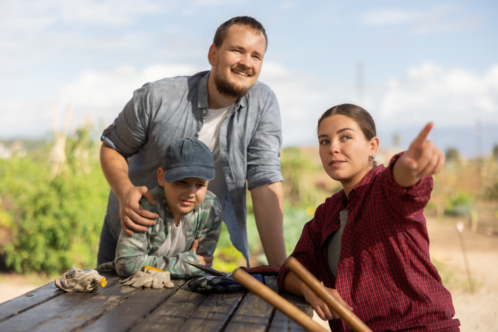 Man woman and boy looking at something in harvest field