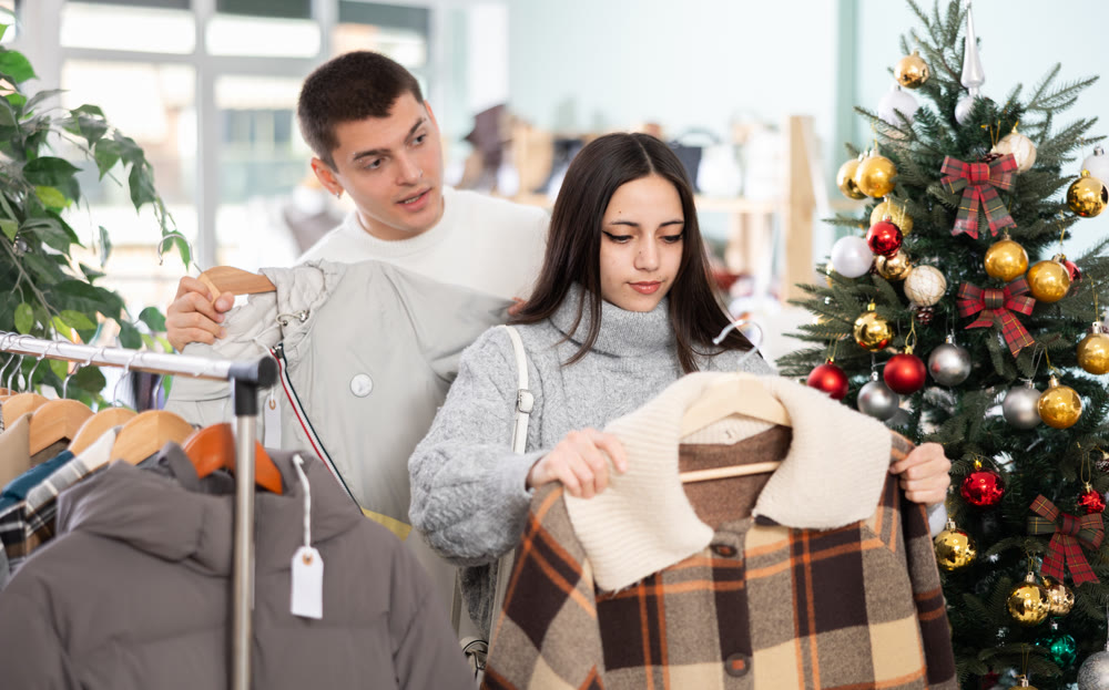 Couple standing in shop and choosing warm winter clothes in Christmas shop