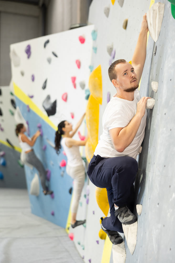 Young man practicing rock climbing on climbing wall