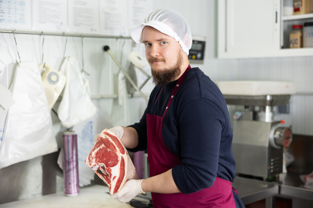 Butcher is demonstraiting meat to clients indoors