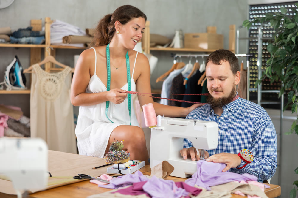 Young female dressmaker working with mannequin while other sews