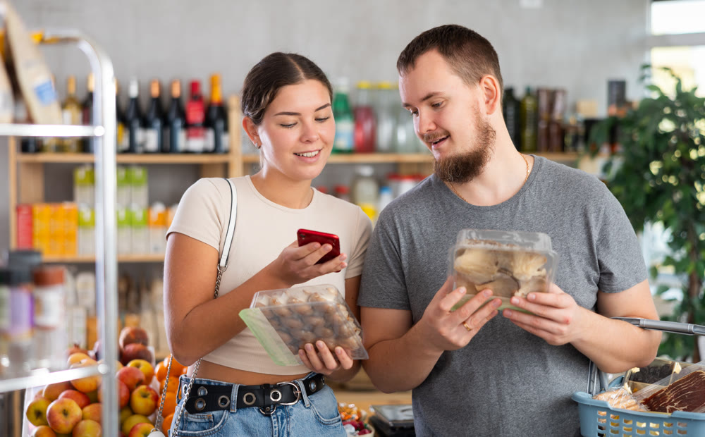 Couple purchaser scanning QR code or barcode of mushrooms in supermarket