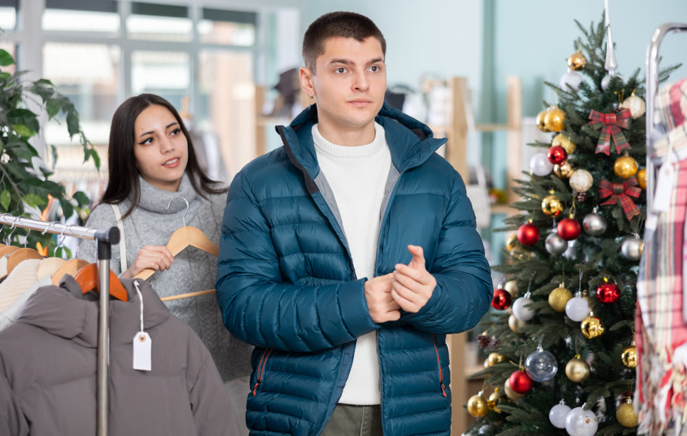 Young guy and his girlfriend try on down jacket