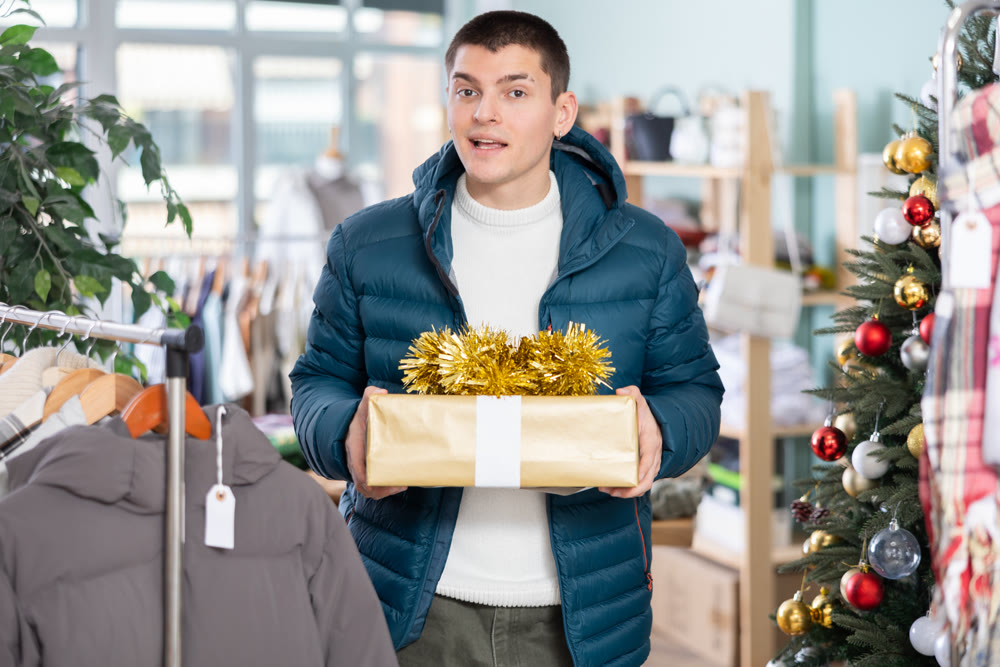 Guy customer with elegant gift box in hands, New Year sale