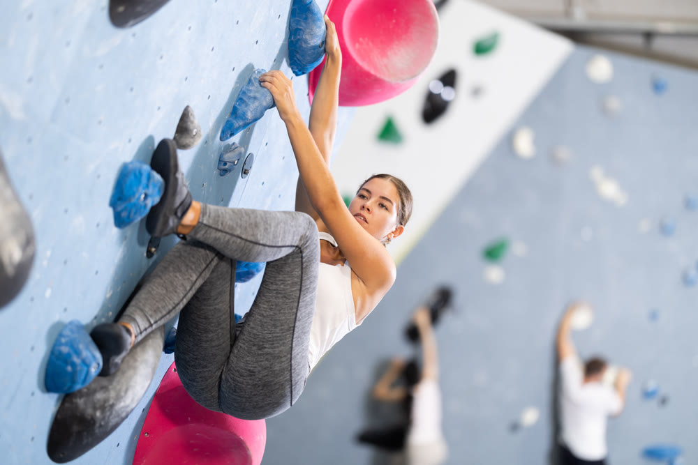 Young woman practicing rock climbing on climbing wall