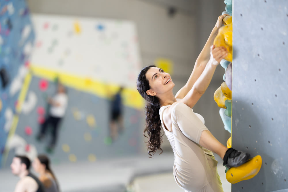 Young woman doing rock climbing on climbing wall