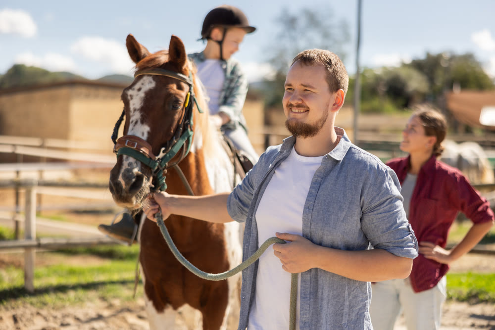 Young man leading horse with boy on horseback