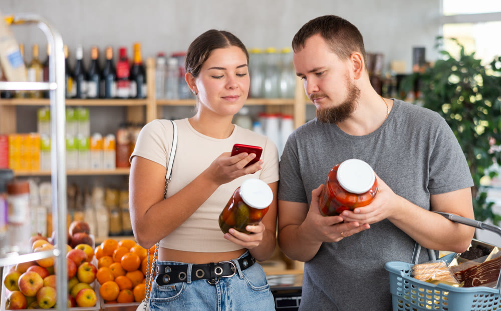 Couple man and woman scanning qr code for pickled cucumbers and tomatoes