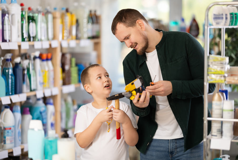 Schoolboy son and dad are choosing hand tools in store