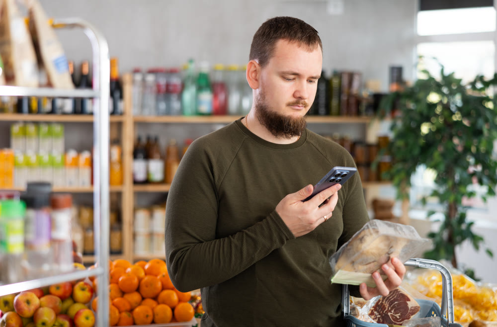 Male purchaser scanning QR code or barcode of oyster mushrooms in supermarket