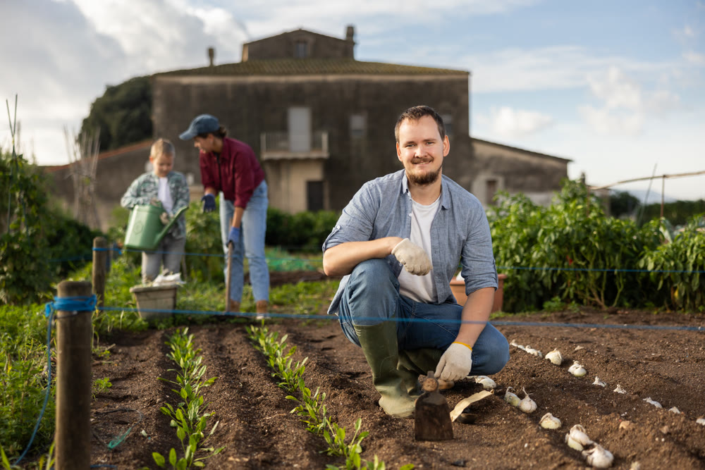 Young man with hoe in field of harvest