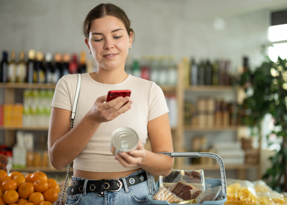 Young woman scanning qr code of canned food
