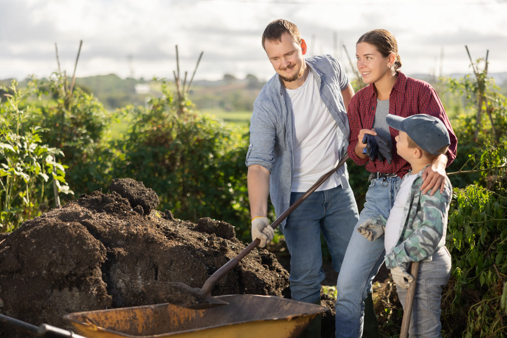 Man woman and boy putting soil in wheelbarrow