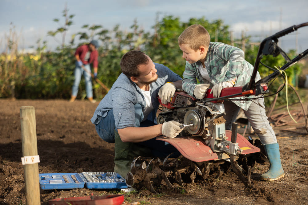 Young man and boy repairing weeding machine