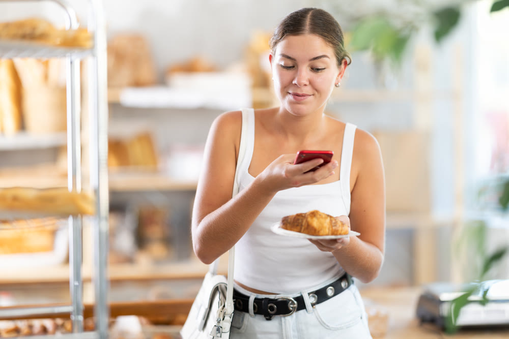 Woman checks calories of croissant using app on phone