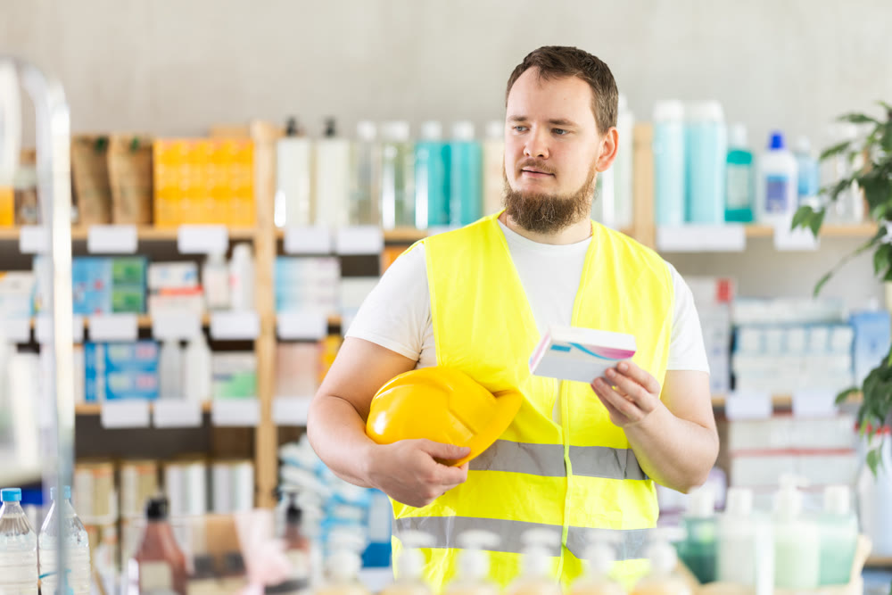 Young man builder chooses pills at pharmacy