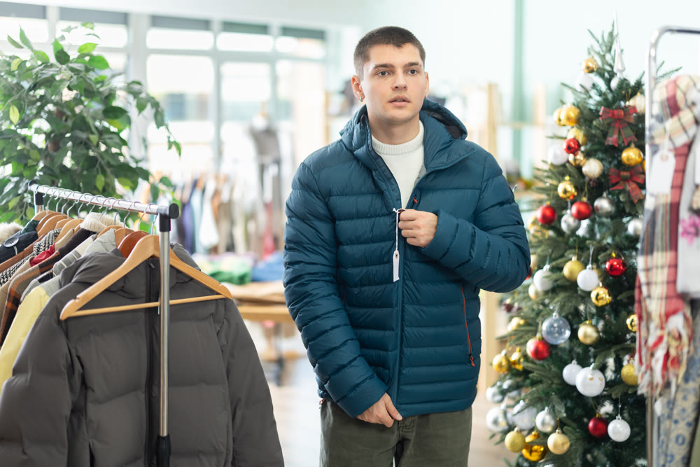 Guy customer is trying on down jacket in store, X mas Eve