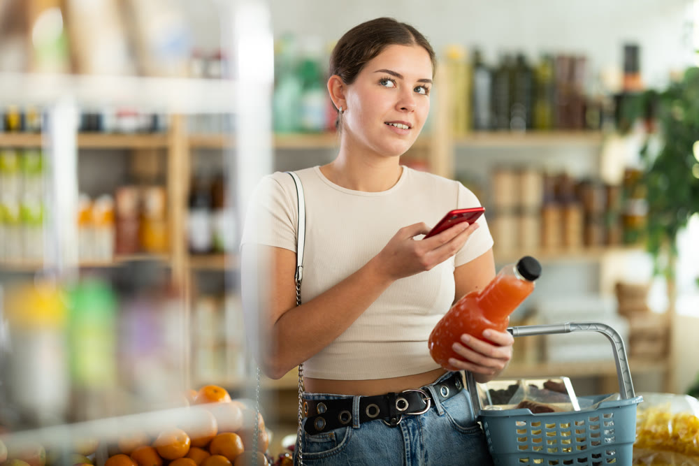 Young woman scanning qr code of grapefruit juice