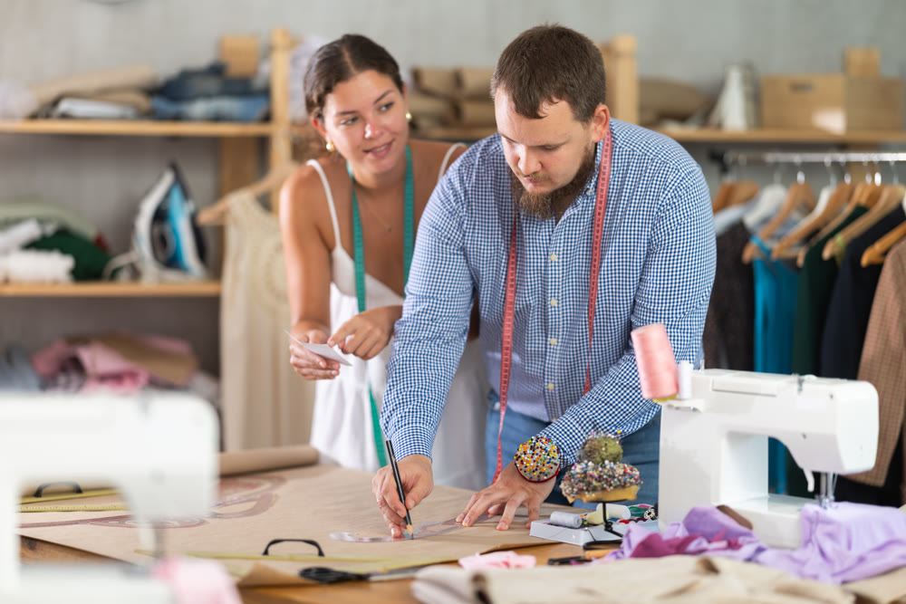 Fashion designers developing garment patterns on paper in studio