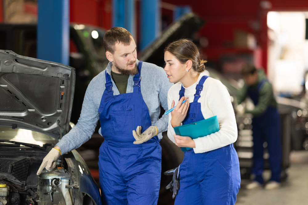 car service worker talks to a mechanic about car repairs