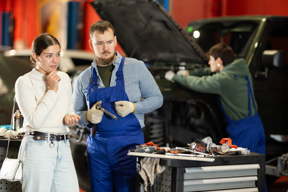 Mechanic checking young woman client car in car service center