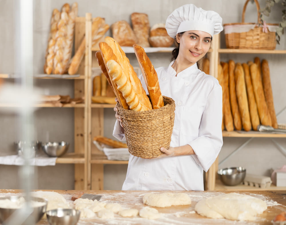 Young female baker with basket of baguettes