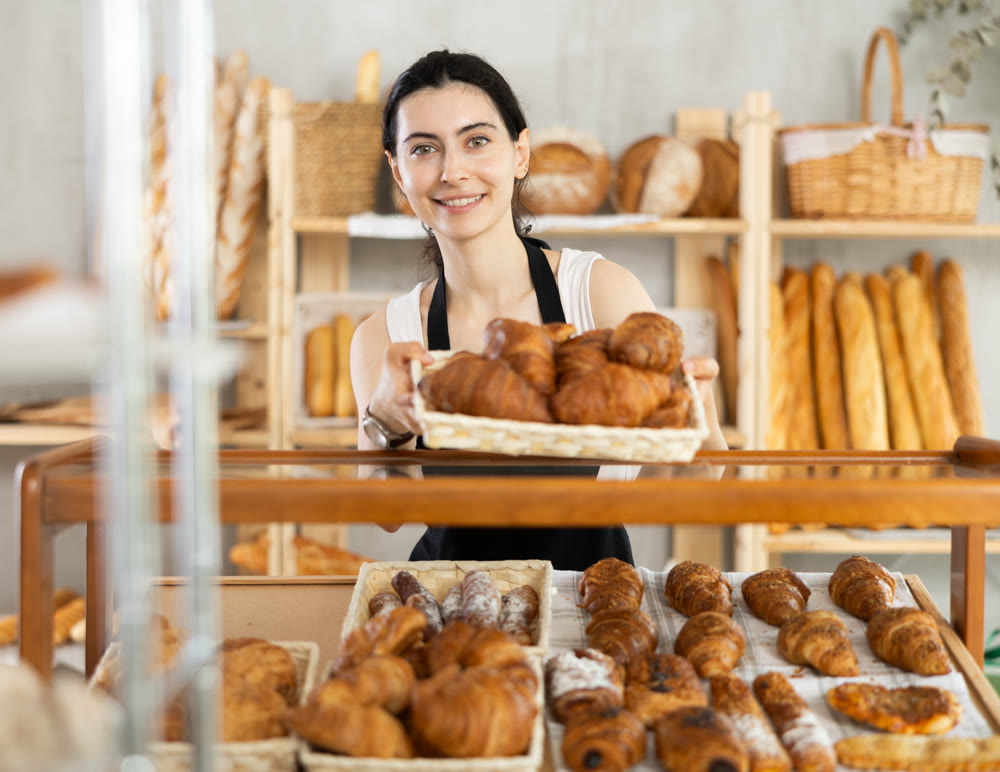 Young woman seller with basket of croissants