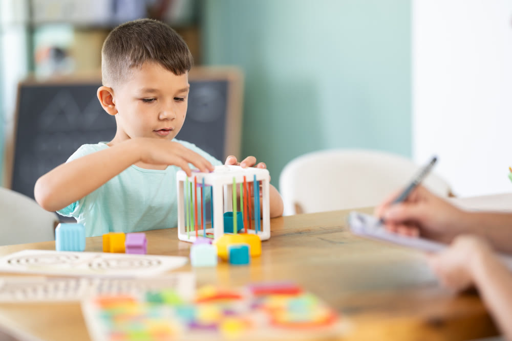 Little boy playing with shape sorter cube during psychological assessment