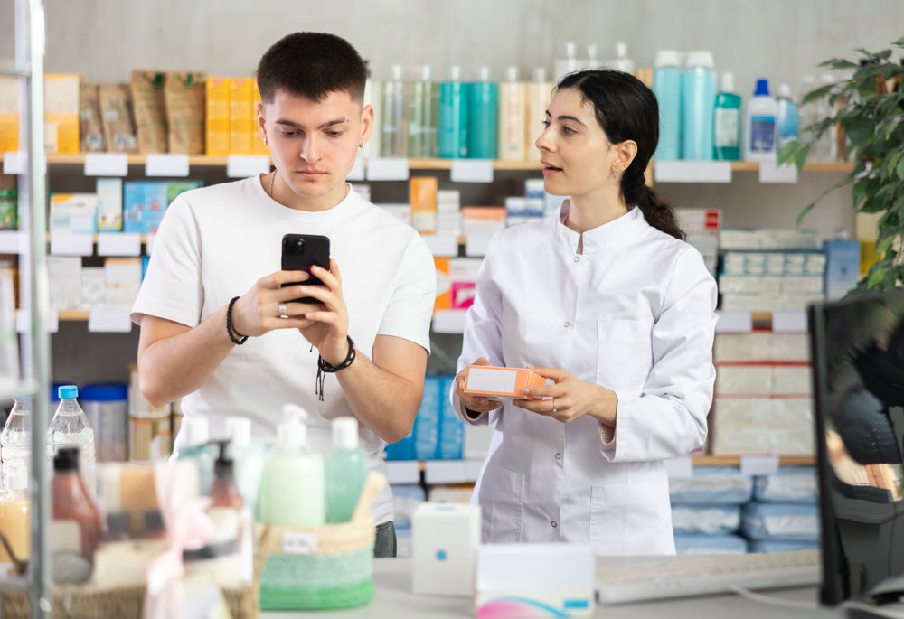 Man scans QR code on box pills label. Female pharmacist offers to choose right shampoo