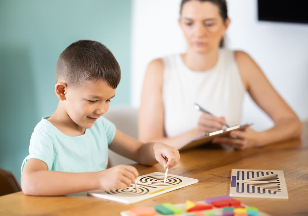 Little boy tracing labyrinths with both hands during psychological test