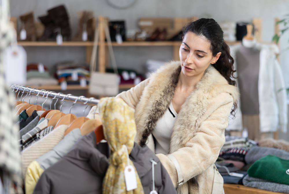 Female shopper chooses jacket in modern clothing store