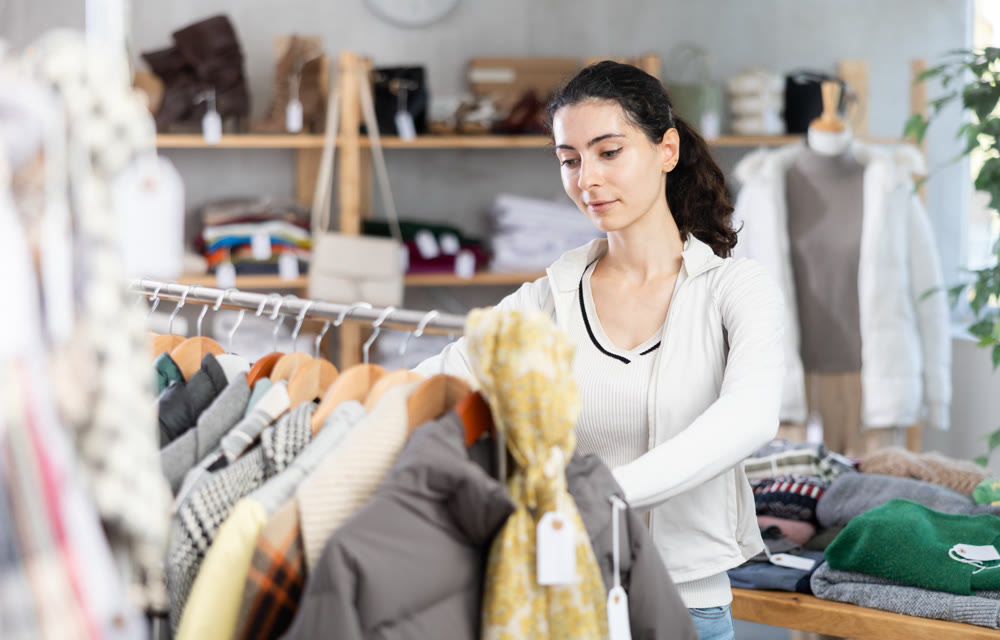 Female shopper selects clothes for autumn winter season in clothing store