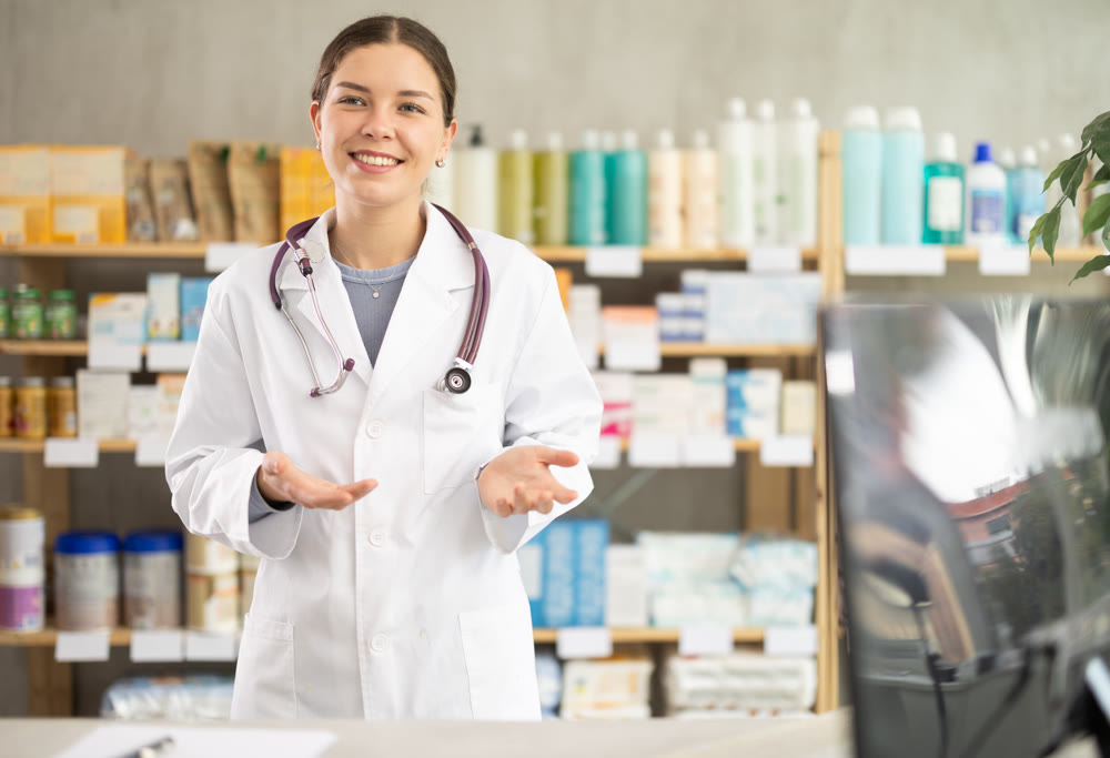 Young female pharmacist welcoming clients in chemist's shop
