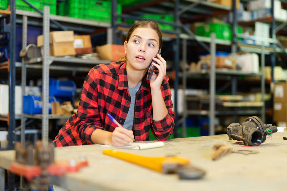 Female worker takes an order on a mobile phone and makes notes in notebook