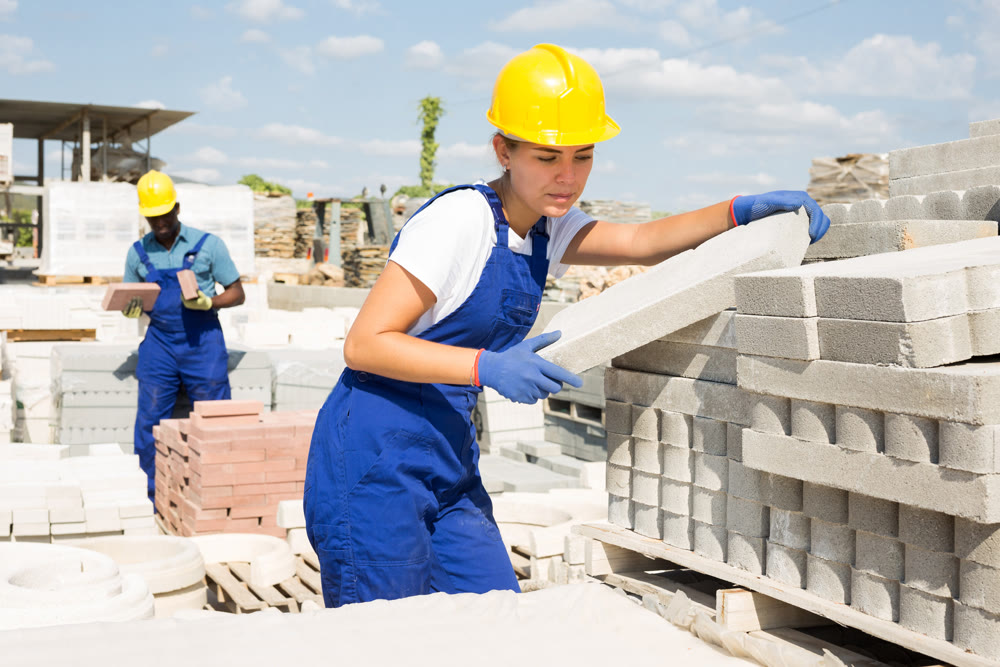 Portrait of a young girl worker laying bricks in a warehouse