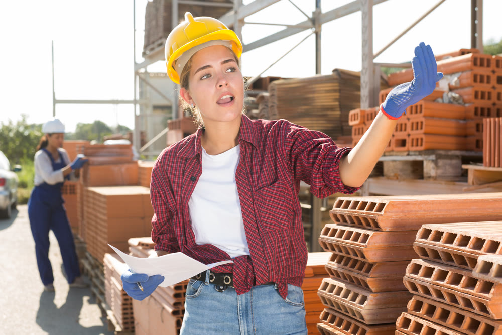 Young female worker who keeps records in a warehouse is calling for someone to help