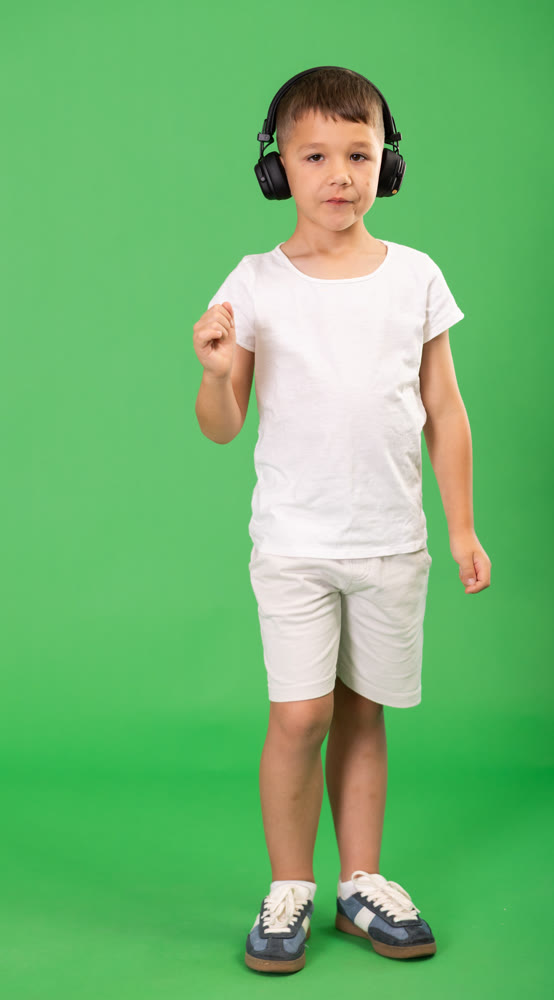 Child boy wearing wired headphones listens to music