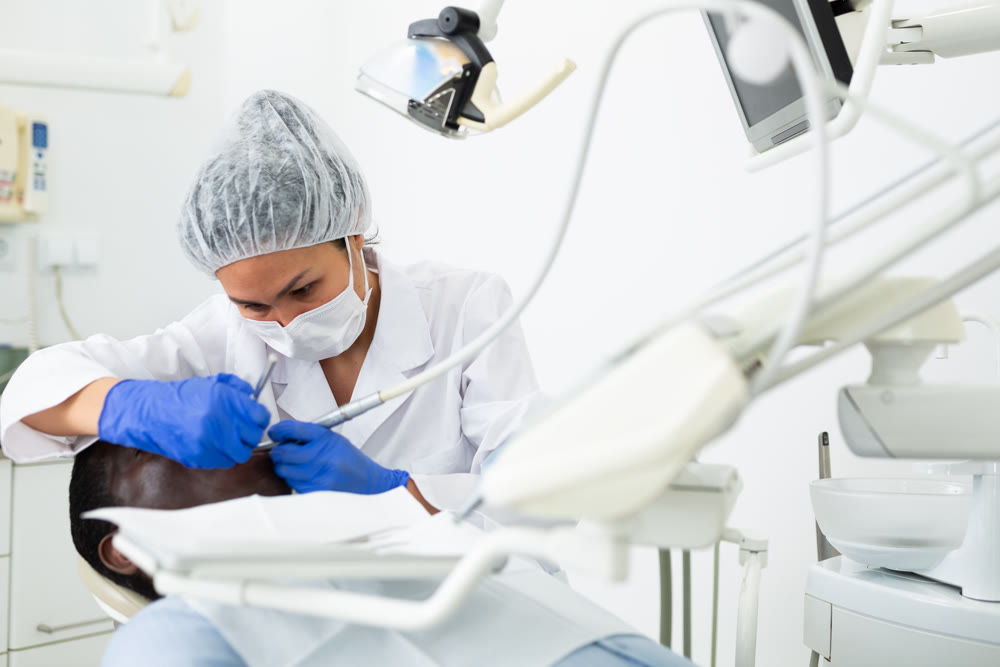 Orthodontist using tools and curing toothache of african-american man