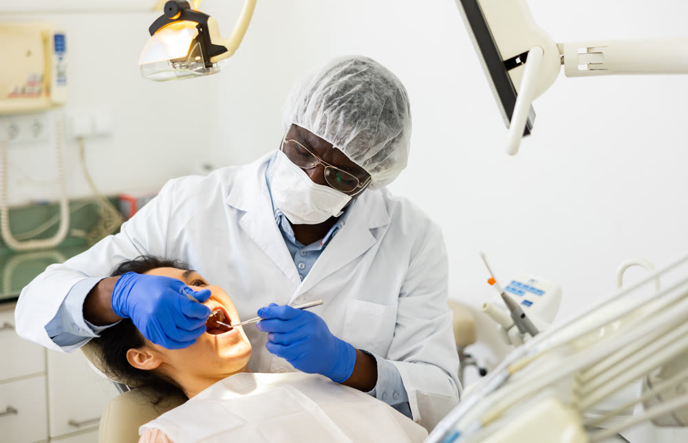 Male dentist using tools for tooth repairing on woman patient