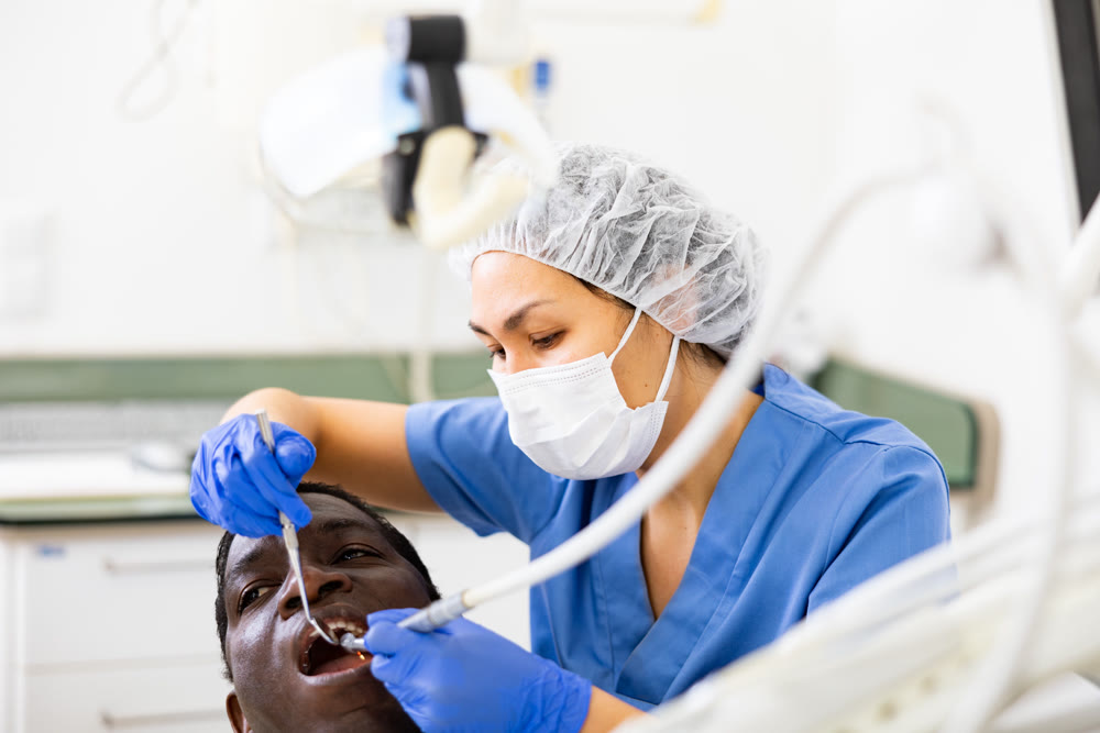 Dentist professional filling teeth for man patient sitting in chair