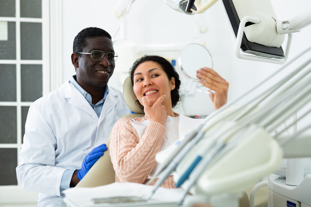 Satisfied dentist with female patient examining results of treatment
