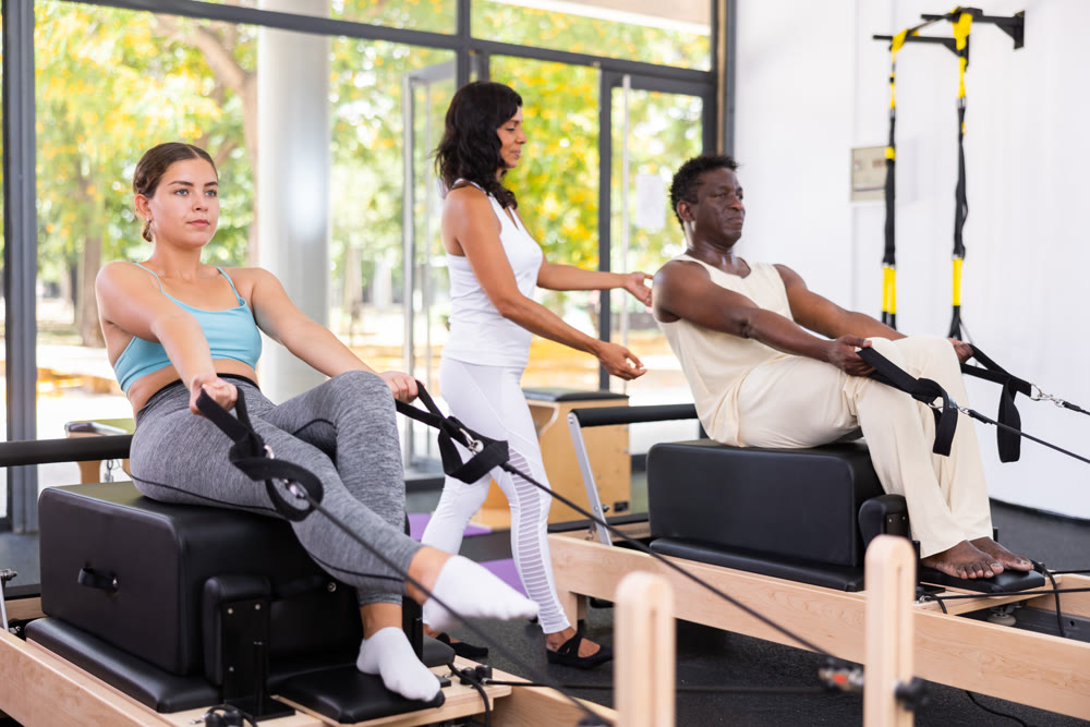 Multethnic group of people training pilates in gym with trainer