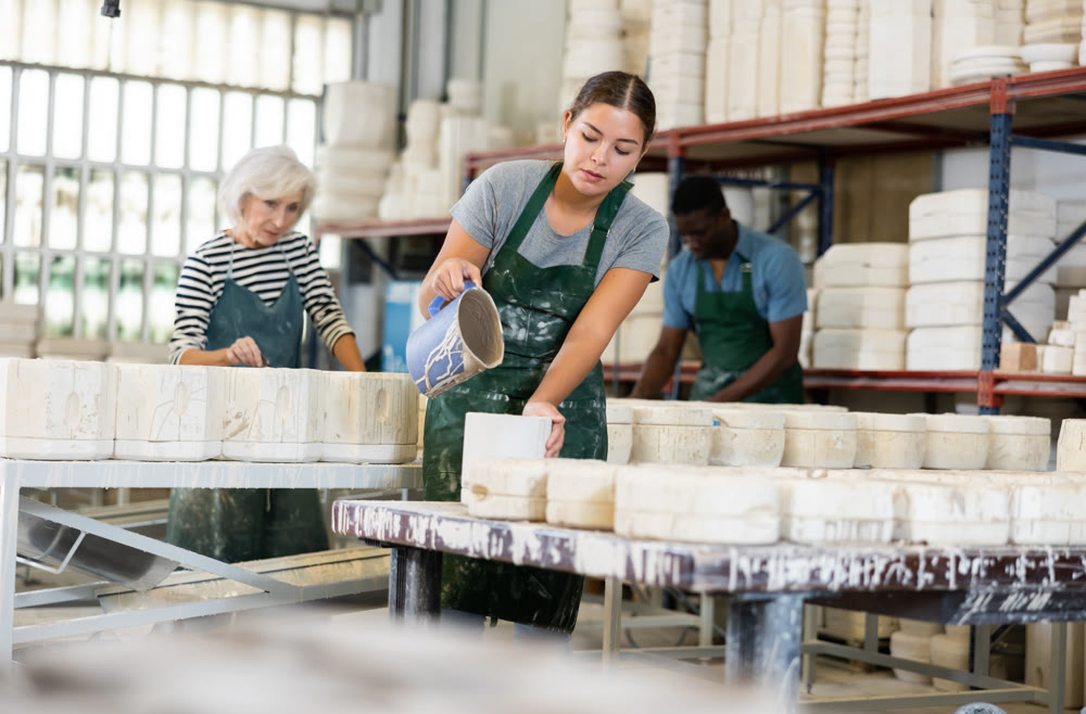 Pouring slip mass into plaster molds at pottery factory