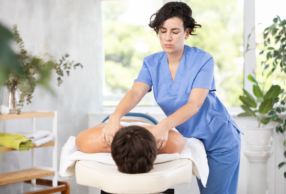 Adult woman giving back massage to young guy