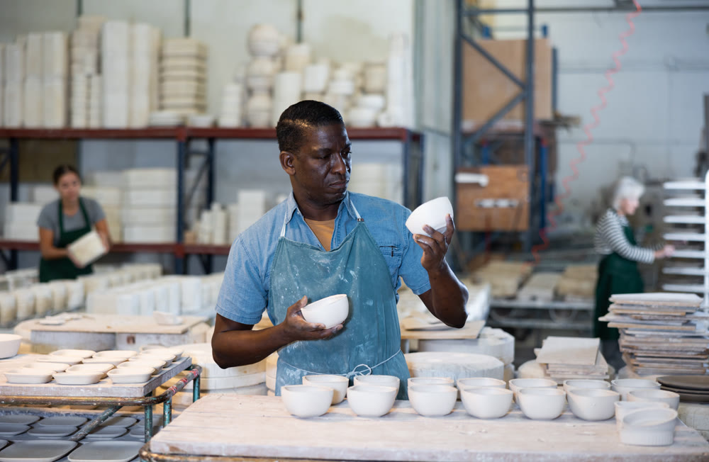 African american man checks quality of pottery after being removed from plaster mold