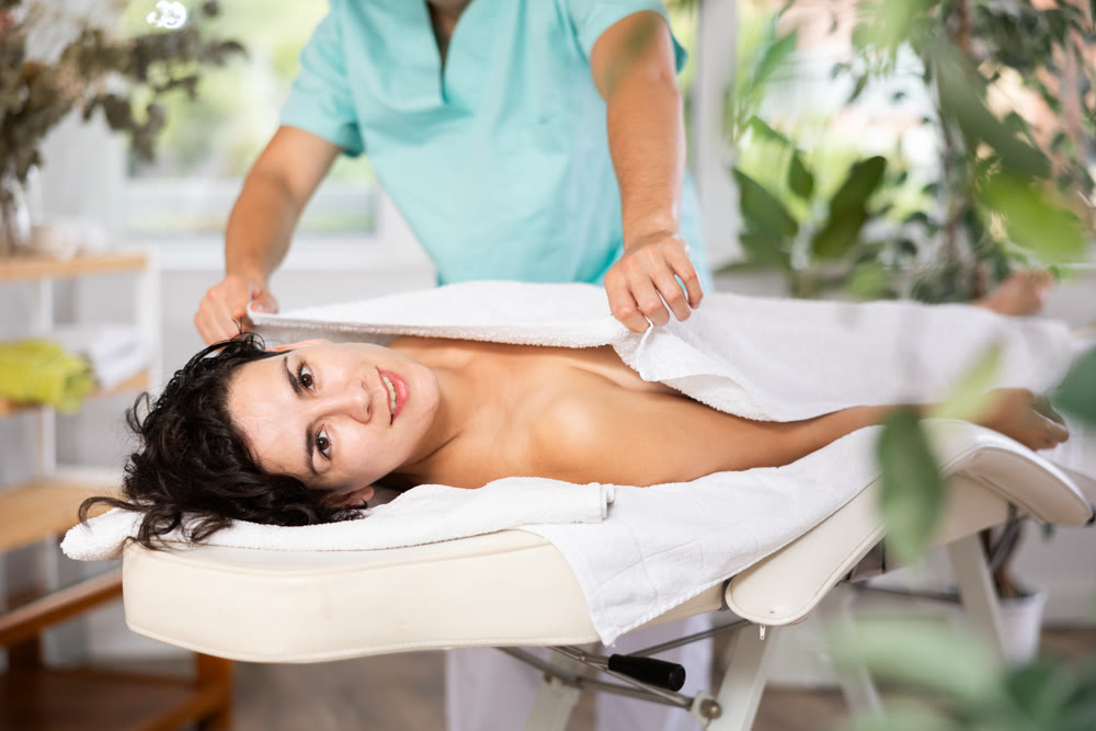 Guy masseur covers adult woman with towel