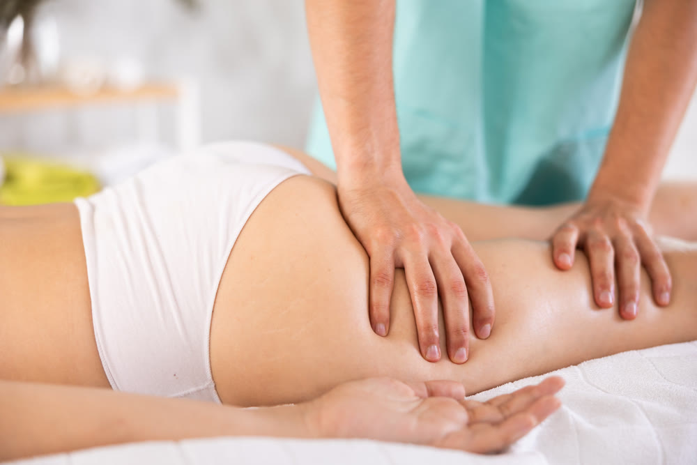 Masseur doing thigh massage to adult woman